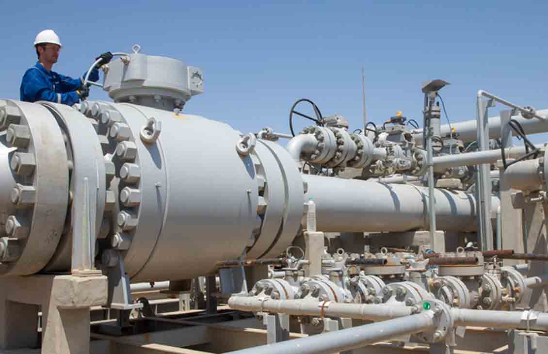 Photo of a worker in blue coveralls working at a gas processing facility