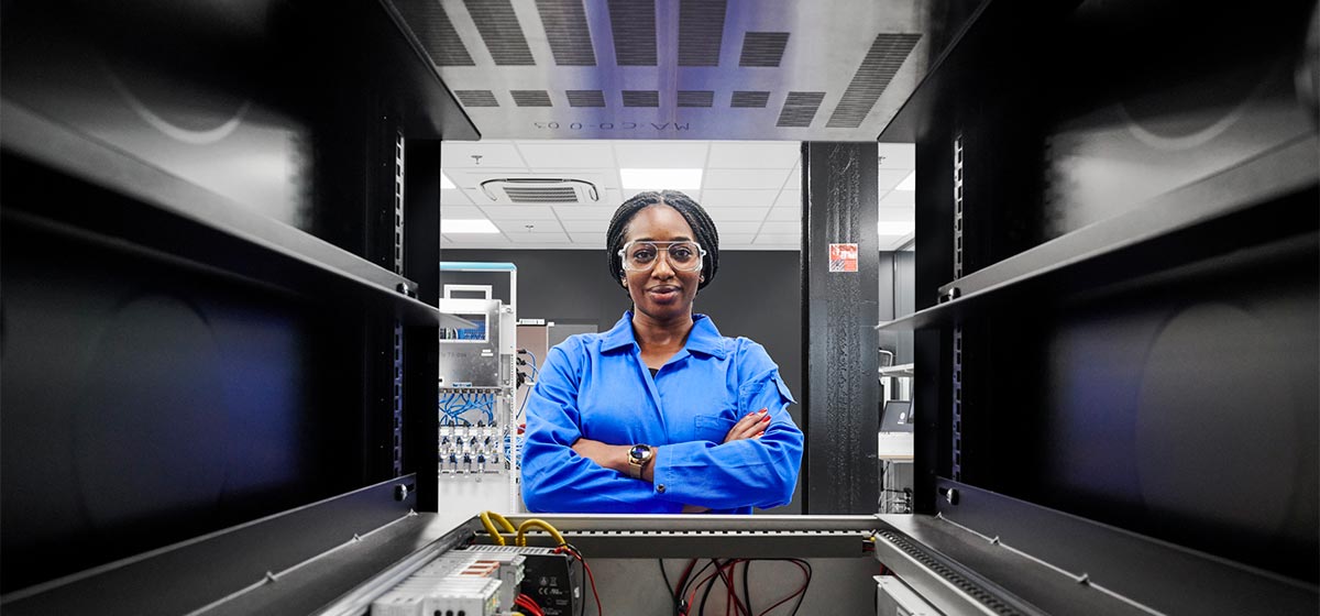 Female operator smiling at the camera through an electrical box