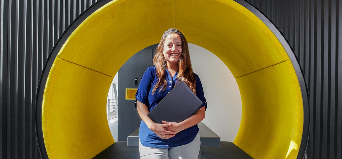 Women holding laptop in front of a big circle yellow structure