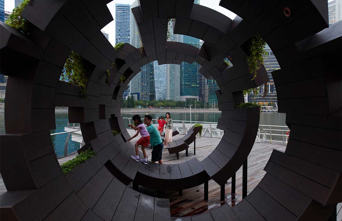 a family and children playing outside on a tubular architectural piece